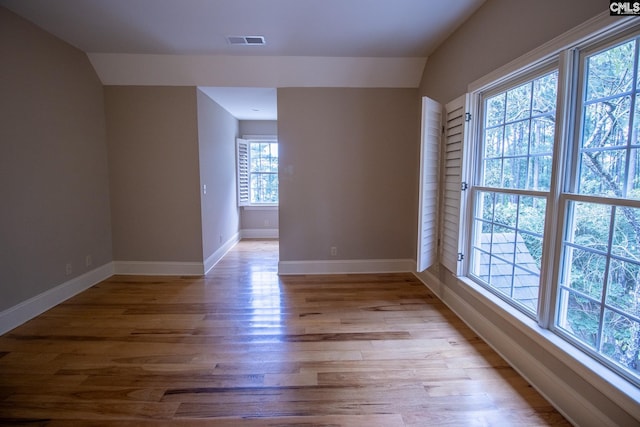 empty room with light hardwood / wood-style floors and vaulted ceiling