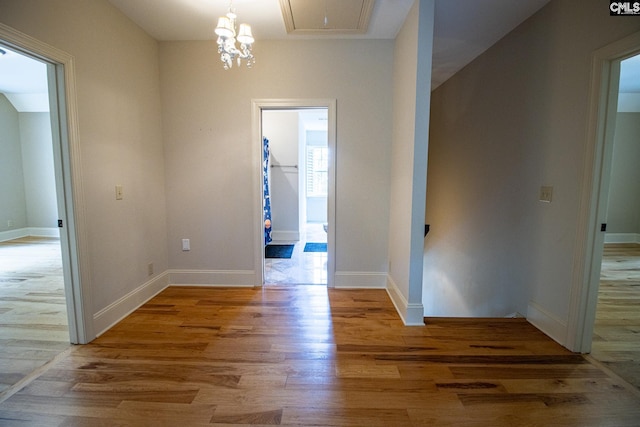 corridor featuring hardwood / wood-style flooring and a notable chandelier