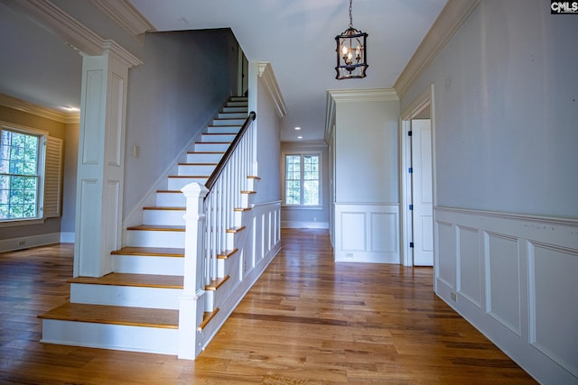 stairway featuring hardwood / wood-style flooring, an inviting chandelier, and crown molding