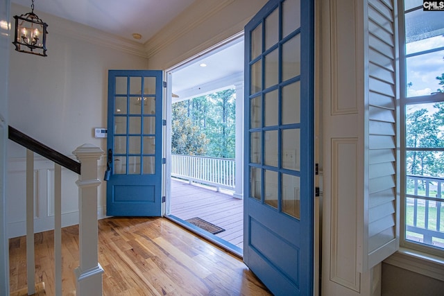 entryway with french doors, wood-type flooring, a notable chandelier, and ornamental molding