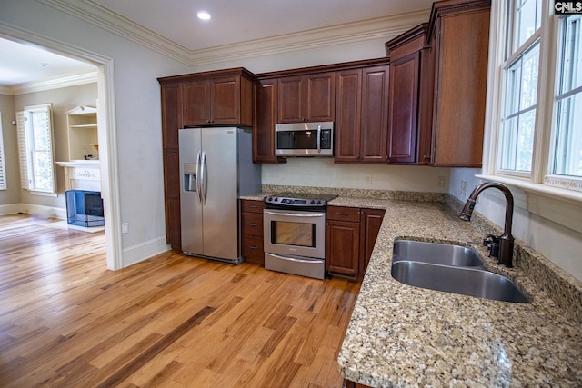 kitchen with sink, light stone counters, light hardwood / wood-style flooring, appliances with stainless steel finishes, and ornamental molding