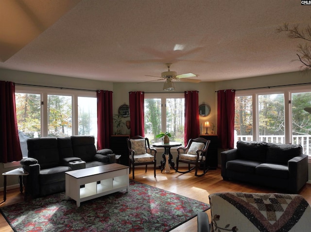 living room with a textured ceiling, light hardwood / wood-style floors, a wealth of natural light, and ceiling fan