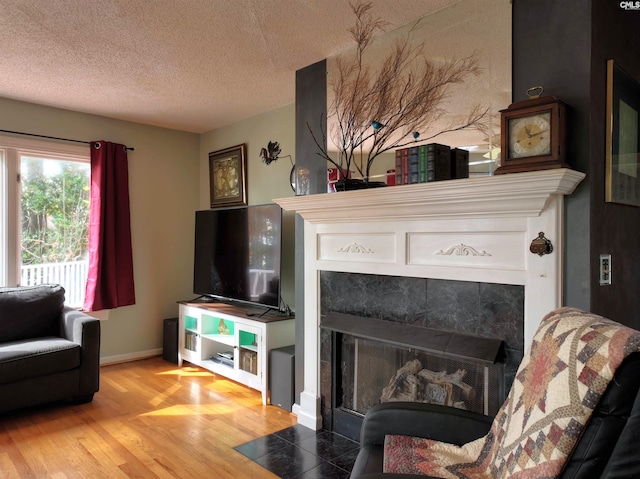 living room featuring hardwood / wood-style floors, a textured ceiling, and a tile fireplace