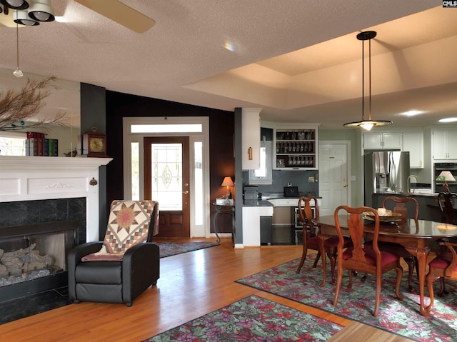 dining area featuring ceiling fan, a textured ceiling, vaulted ceiling, a fireplace, and hardwood / wood-style flooring