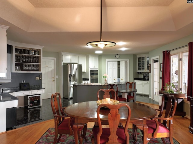 dining room featuring a raised ceiling, dark hardwood / wood-style flooring, and beverage cooler