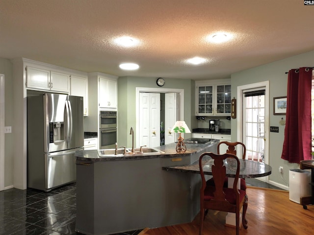 kitchen featuring white cabinetry, sink, stainless steel appliances, a textured ceiling, and a kitchen island