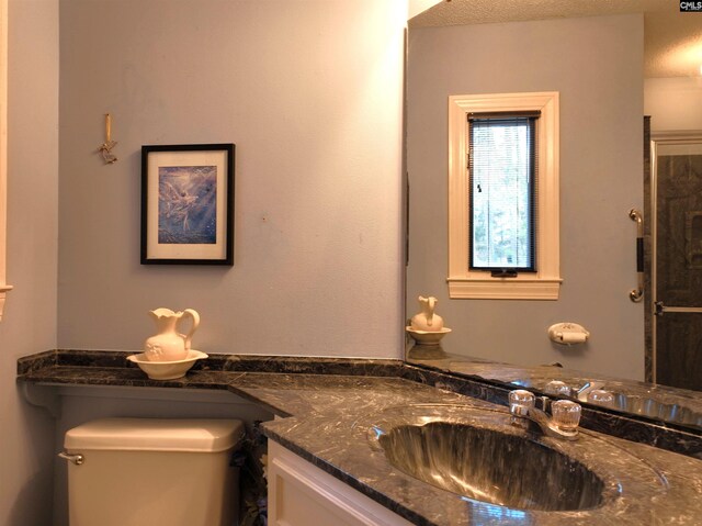 bathroom with a textured ceiling, vanity, and toilet