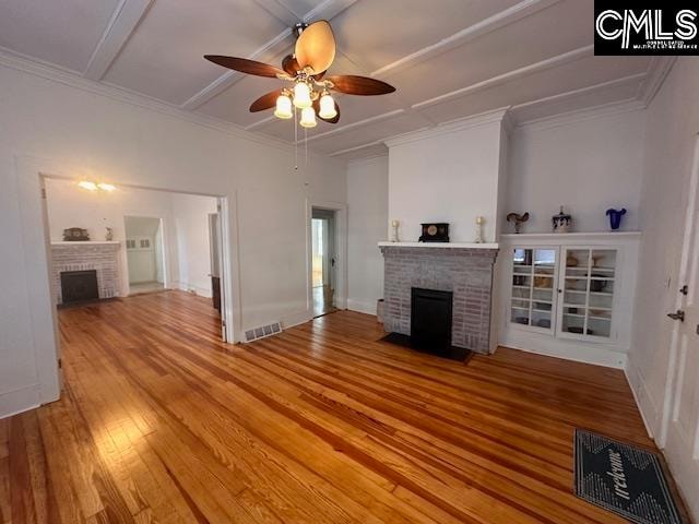 unfurnished living room featuring hardwood / wood-style flooring, a brick fireplace, ceiling fan, and ornamental molding