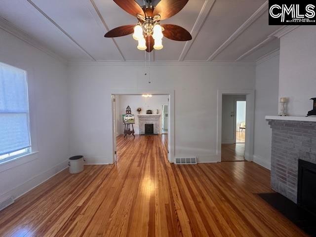 unfurnished living room featuring a fireplace, light hardwood / wood-style flooring, ceiling fan, and ornamental molding