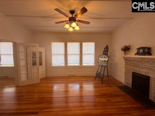 unfurnished living room featuring hardwood / wood-style floors, plenty of natural light, ceiling fan, and a fireplace