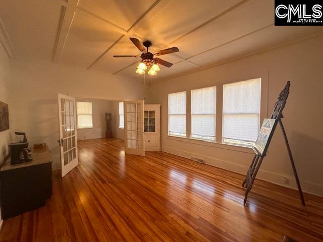 unfurnished living room featuring french doors, ceiling fan, plenty of natural light, and wood-type flooring