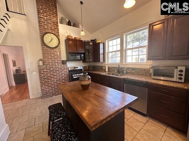 kitchen with a center island, sink, appliances with stainless steel finishes, decorative light fixtures, and dark brown cabinetry