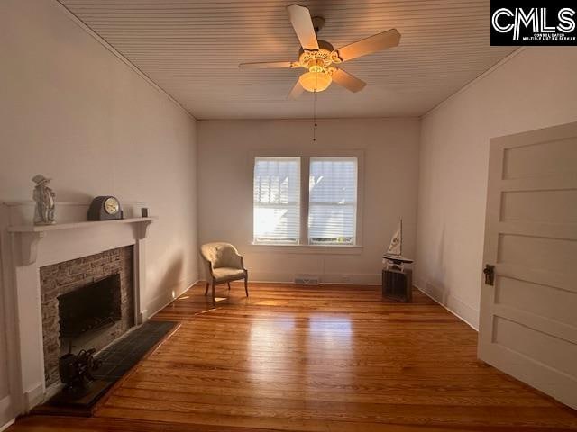 unfurnished room featuring a stone fireplace, ceiling fan, and hardwood / wood-style floors