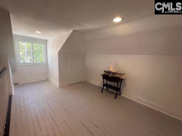 additional living space with hardwood / wood-style flooring and lofted ceiling