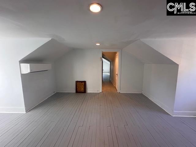 bonus room featuring hardwood / wood-style floors, a wall mounted air conditioner, and lofted ceiling