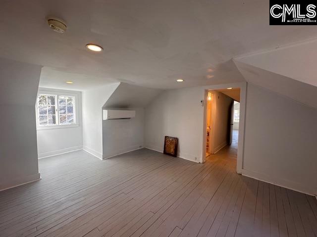 bonus room with hardwood / wood-style flooring, a wall unit AC, and lofted ceiling