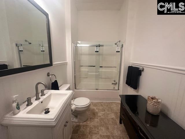 full bathroom featuring sink, enclosed tub / shower combo, and toilet