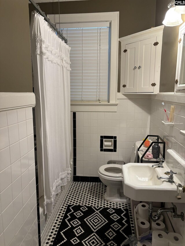 full bathroom with sink, shower / bath combination with curtain, tile walls, and toilet