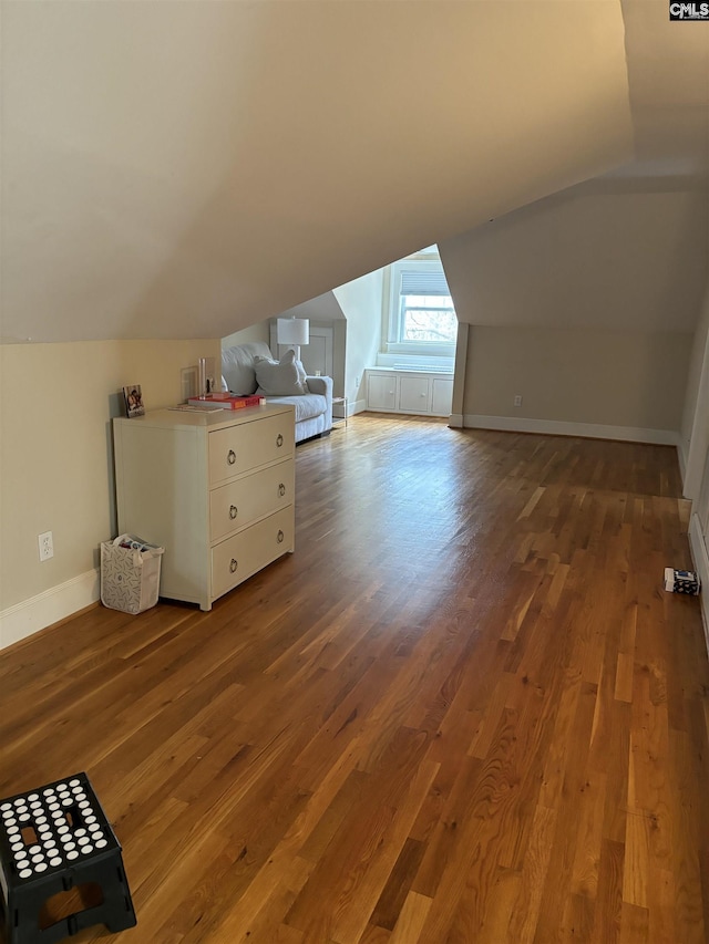 additional living space with hardwood / wood-style floors and lofted ceiling