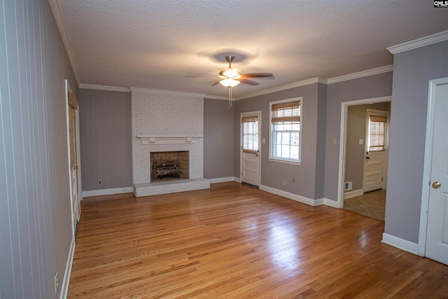 unfurnished living room with a fireplace, a textured ceiling, light hardwood / wood-style floors, and ornamental molding