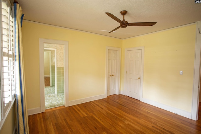 unfurnished bedroom featuring a textured ceiling, ceiling fan, and dark wood-type flooring