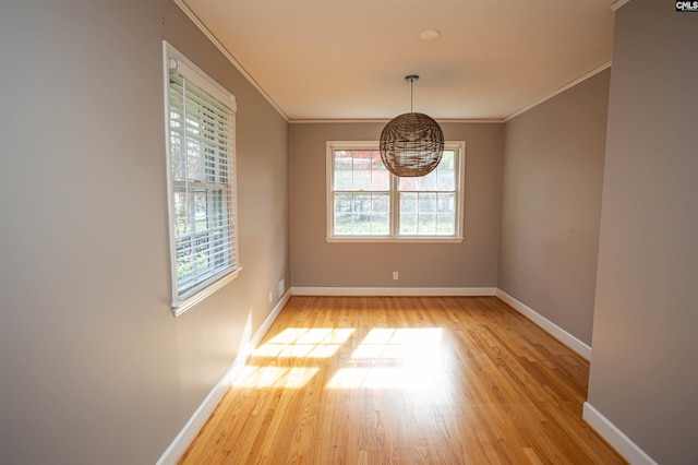 unfurnished dining area with light wood-type flooring and crown molding