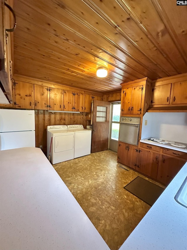 kitchen with washer and clothes dryer, white appliances, wooden walls, and wooden ceiling