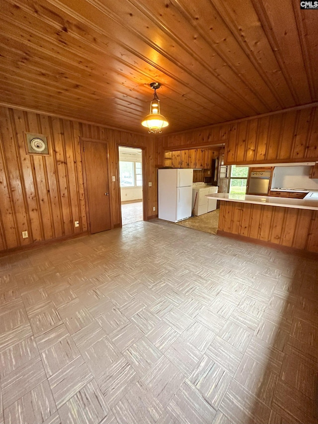 kitchen with white refrigerator, hanging light fixtures, wooden walls, wood ceiling, and washer / clothes dryer