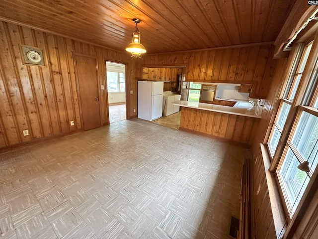 kitchen with kitchen peninsula, white fridge, wooden walls, light parquet flooring, and wood ceiling