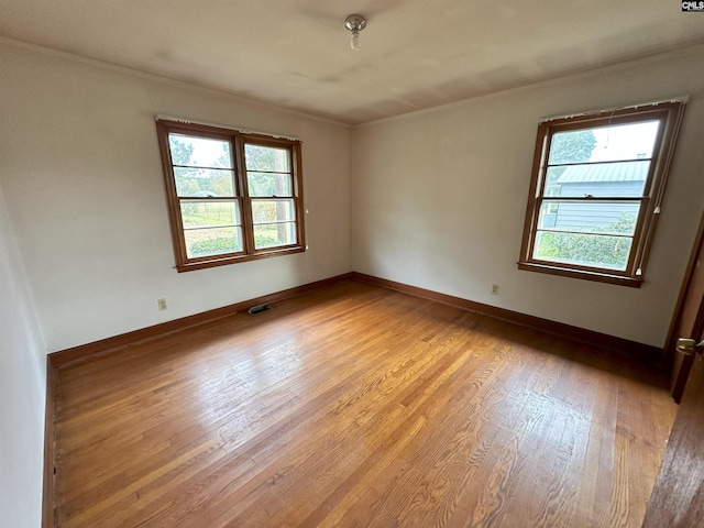 unfurnished room featuring ornamental molding, light hardwood / wood-style floors, and a healthy amount of sunlight