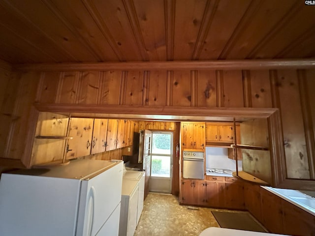 kitchen featuring independent washer and dryer, white appliances, wood ceiling, and wood walls