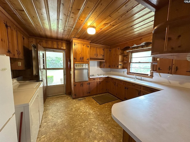 kitchen with stainless steel oven, sink, wooden ceiling, white gas stovetop, and washer and clothes dryer