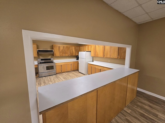 kitchen with dark hardwood / wood-style floors, white refrigerator, a drop ceiling, and stainless steel range