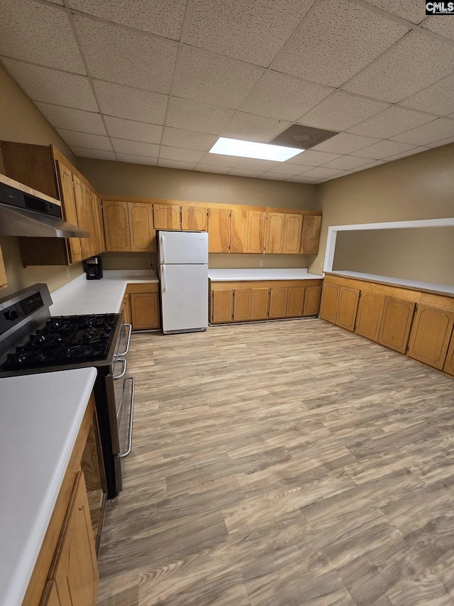 kitchen featuring a drop ceiling, white fridge, light hardwood / wood-style floors, and stainless steel stove