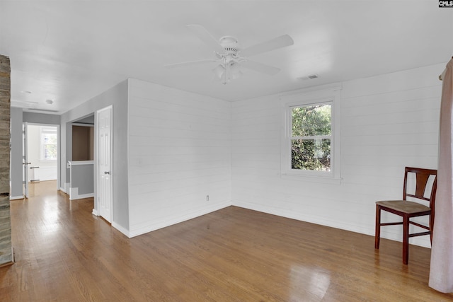 empty room featuring wood-type flooring, a wealth of natural light, and ceiling fan