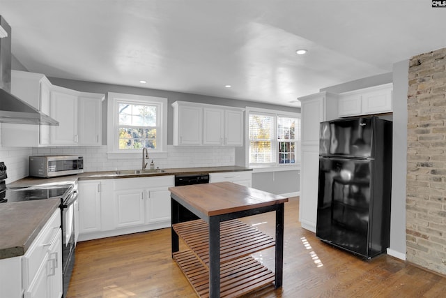 kitchen with sink, light wood-type flooring, wall chimney exhaust hood, and black appliances