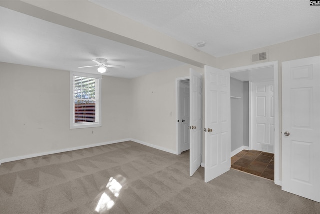 unfurnished bedroom featuring light carpet, ceiling fan, and a textured ceiling