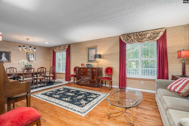 living room with wood-type flooring, a textured ceiling, and a notable chandelier