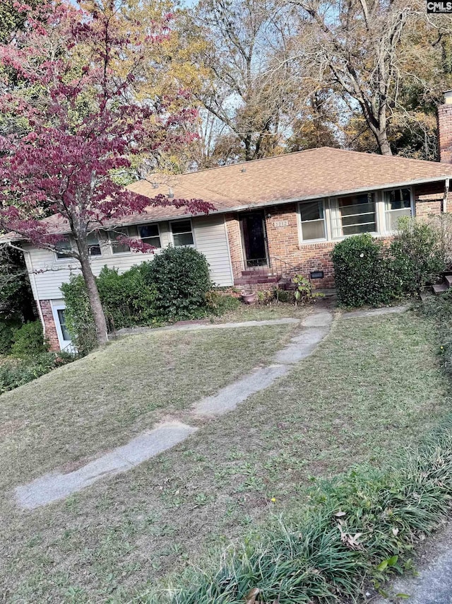 ranch-style house with brick siding, a chimney, and a front yard