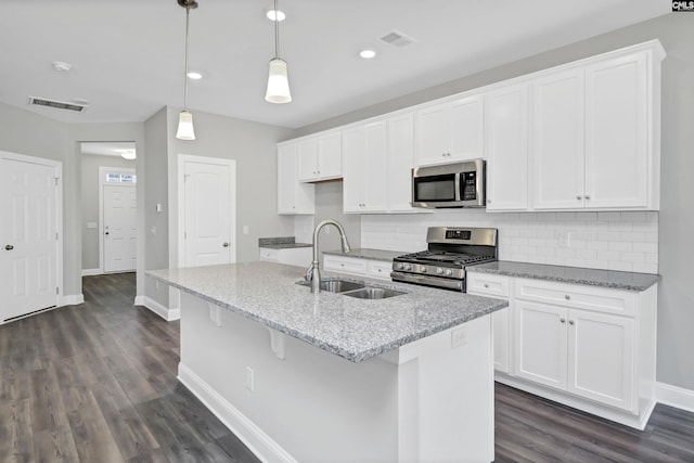 kitchen featuring a kitchen island with sink, sink, hanging light fixtures, and appliances with stainless steel finishes