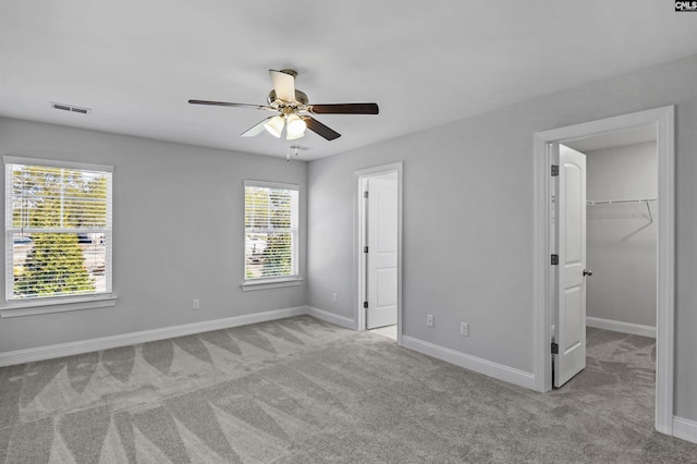 unfurnished bedroom with ceiling fan, light colored carpet, a spacious closet, and a closet