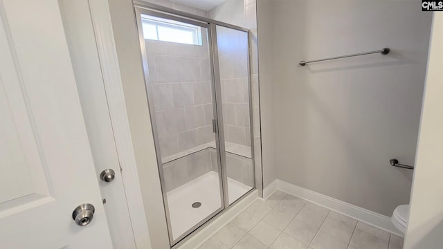 bathroom with toilet, tile patterned floors, and a shower with door