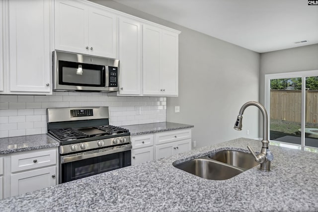 kitchen featuring decorative backsplash, appliances with stainless steel finishes, light stone counters, sink, and white cabinetry