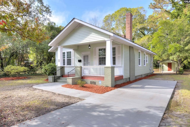 bungalow-style house featuring a porch and a storage unit