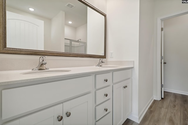 bathroom with wood-type flooring, vanity, and a shower with shower door