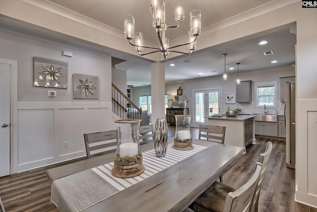 dining area with crown molding, sink, dark wood-type flooring, and a chandelier
