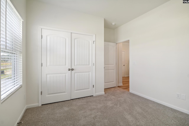 unfurnished bedroom with light colored carpet and a closet