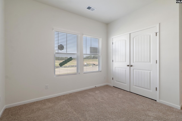 unfurnished bedroom with light colored carpet and a closet