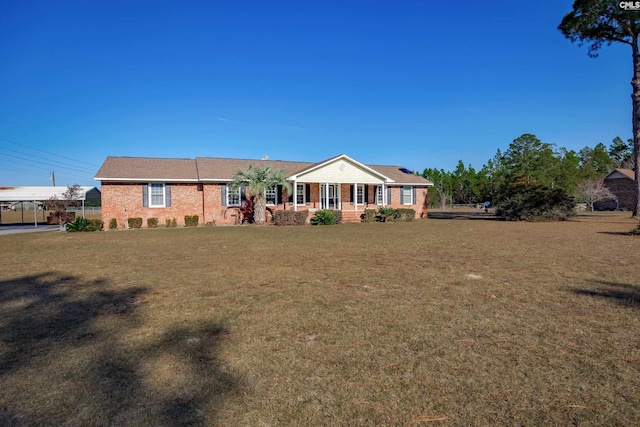 ranch-style home featuring covered porch and a front lawn