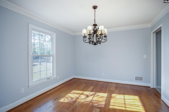 empty room featuring crown molding, wood-type flooring, and an inviting chandelier